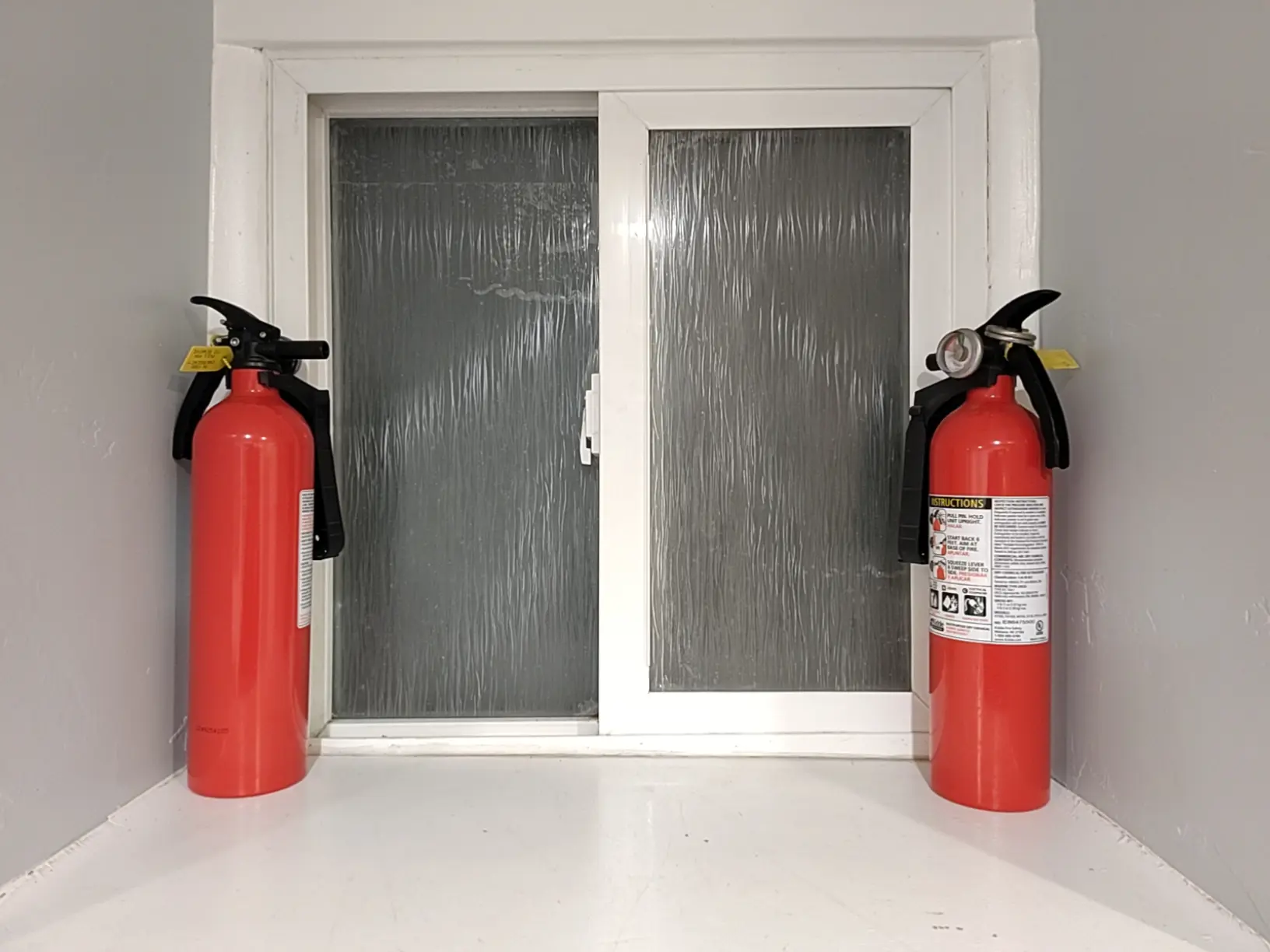 two fire extinguishers by a window