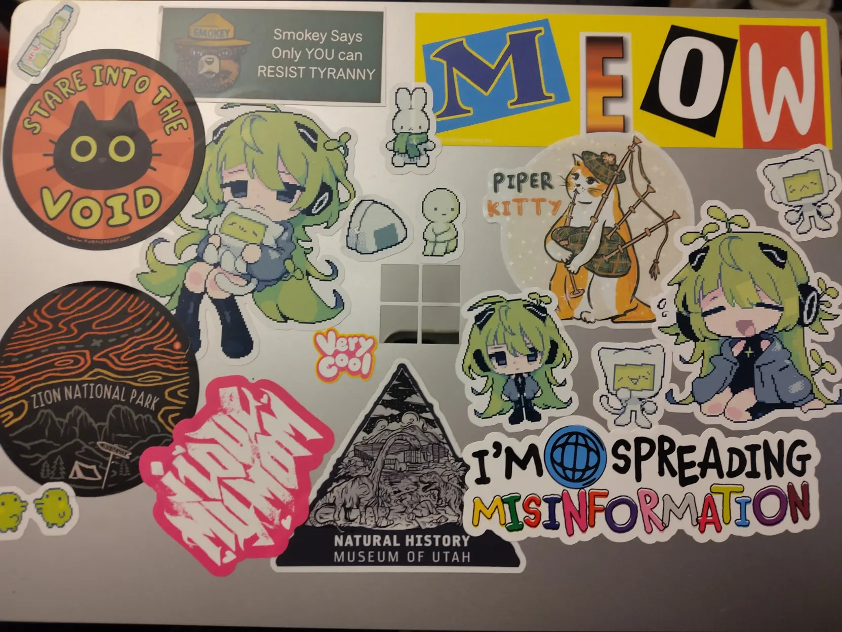 my surface laptop with many stickers, including national history museum of utah, zion national park, multiple kael stickers, a cat playing bagpipes, smokey says only you can resist tyranny, meow, im spreading misinformation, and others
