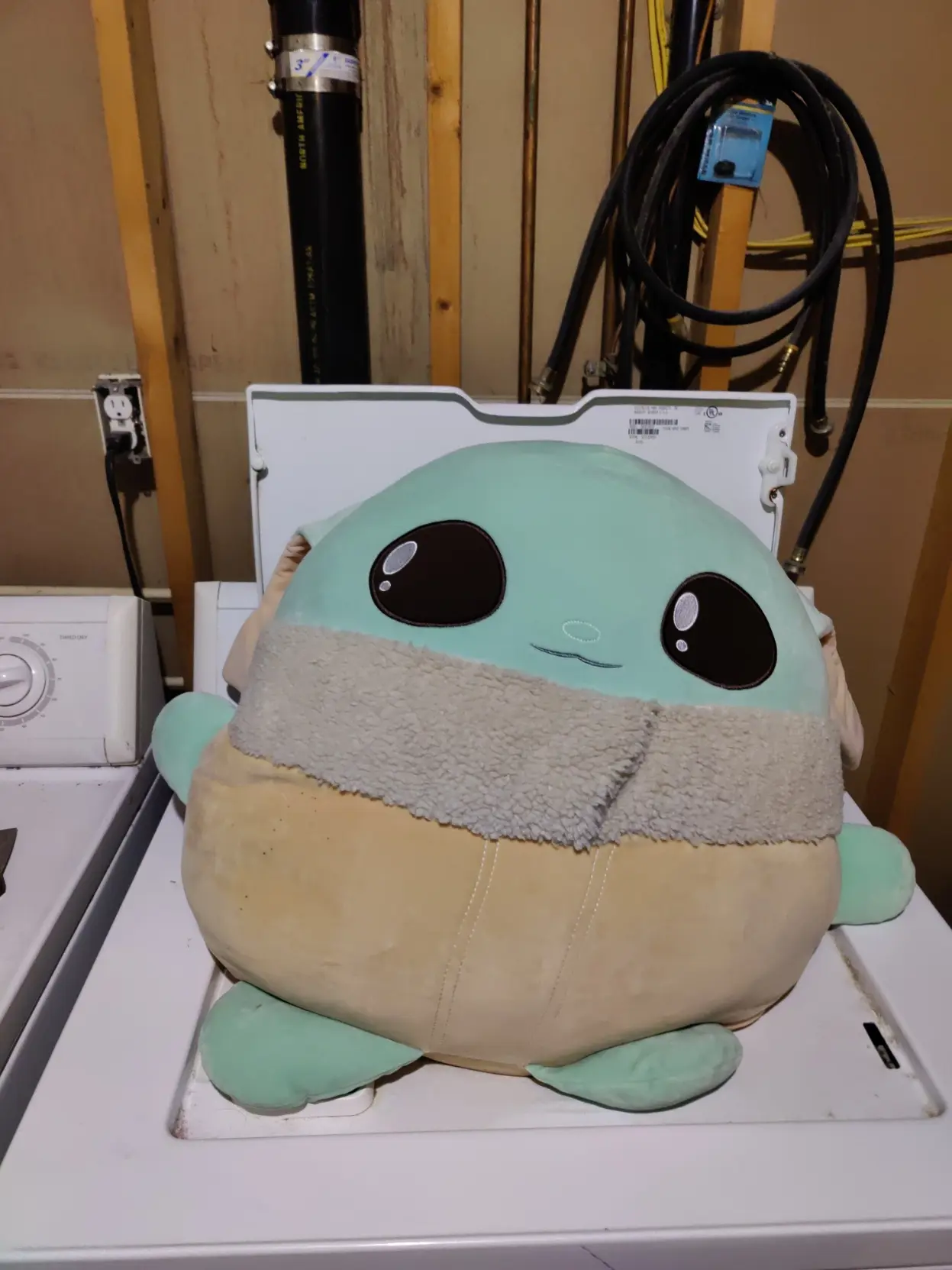 big ass grogu plushy sitting on an open washing machine
